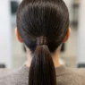Close-up view of sleek ponytail base showing hair gathering mechanics and wrapped elastic detail