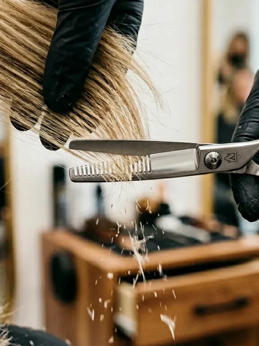 Extreme close-up of thinning shears cutting through layered hair ends with falling hair fragments