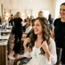 Woman with completed wedding hair down style looking delighted in bright salon mirror