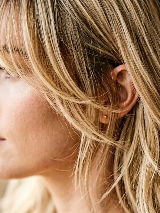 Woman with wispy layered bangs showing soft texture and movement in blonde hair