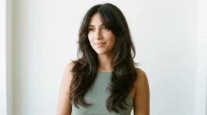 Woman with long dark brown 90s layered blowout and curtain bangs in bright studio light