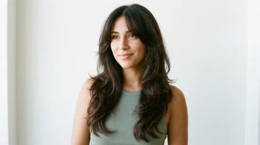 Woman with long dark brown 90s layered blowout and curtain bangs in bright studio light
