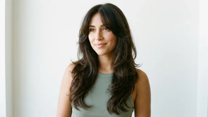 Woman with long dark brown 90s layered blowout and curtain bangs in bright studio light