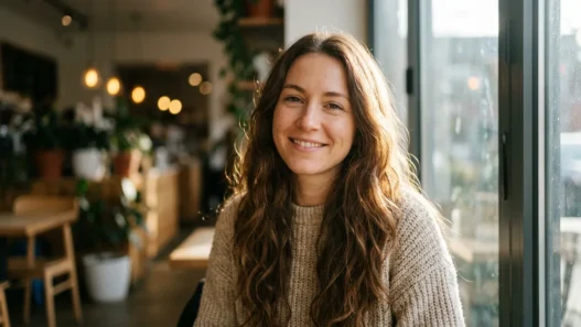 Woman with long chestnut loose waves standing by a bright cafe window with soft side light