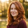 Woman with burnished copper layered medium hair glowing in golden hour sunlight outdoors