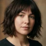 Woman with chin-length espresso brown shaggy bob showing feathered ends in soft light