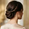 Woman with long dark brown hair in finished low twisted updo viewed from behind