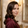 Woman with long glossy Hollywood waves and deep side part in marble powder room