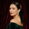 Woman with sleek low chignon and velvet bow in formal portrait against burgundy backdrop