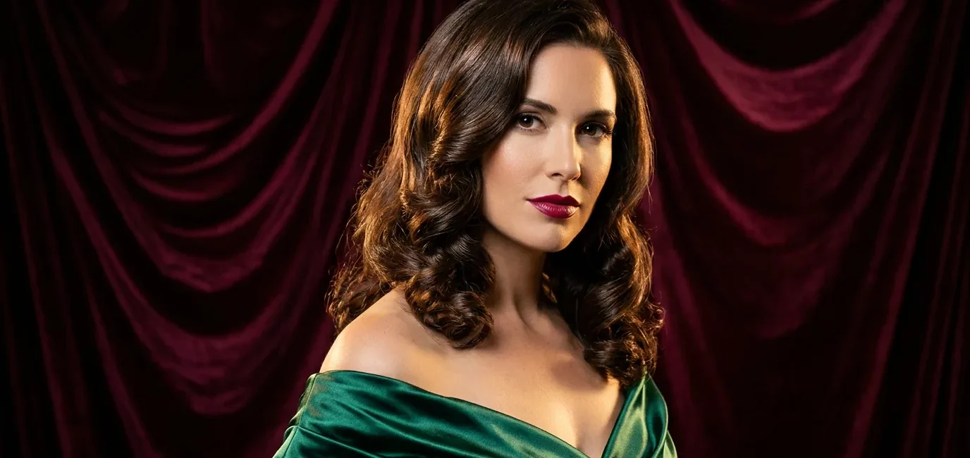 Woman with medium glossy brunette holiday waves posing against burgundy velvet backdrop in studio light