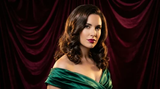 Woman with medium glossy brunette holiday waves posing against burgundy velvet backdrop in studio light
