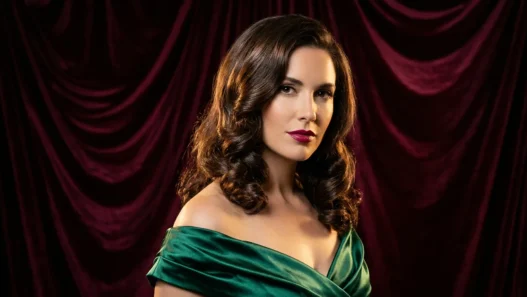 Woman with medium glossy brunette holiday waves posing against burgundy velvet backdrop in studio light