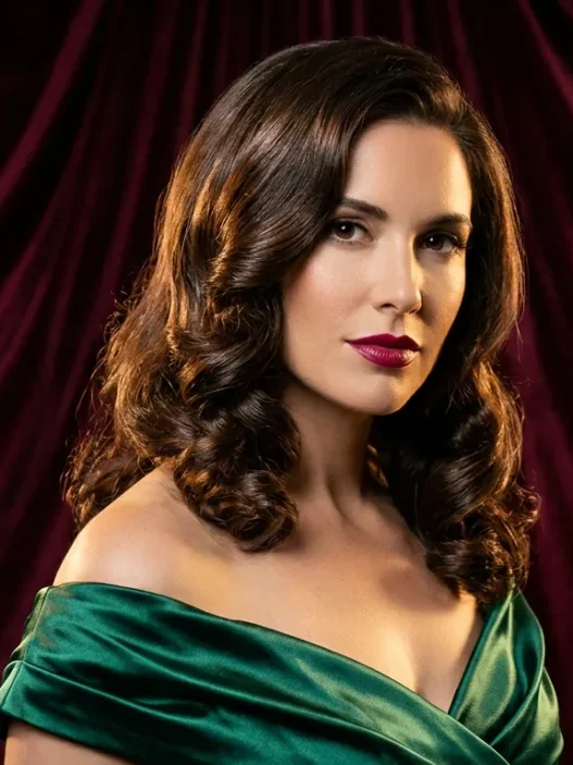 Woman with medium glossy brunette holiday waves posing against burgundy velvet backdrop in studio light