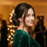 Woman with low holiday chignon and pearl pins glowing under warm party lights
