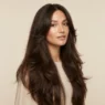Woman with very long dark brown butterfly haircut and soft face framing layers in studio light