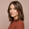 Woman with glossy collarbone brunette hair and soft face framing layers in studio light