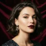 Woman with chin-length tousled brunette bob against burgundy velvet backdrop in studio light