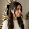 Woman with long dark brown half-up hair wearing black velvet bow at crown in soft light