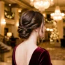 Woman with low twisted chignon in grand hotel lobby under warm chandelier light